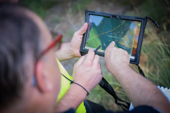 Cartographie et planification forestière sur le terrain – ARGEFO Technicien forestier utilisant une tablette numérique avec interface cartographique pour planifier des interventions sylvicoles sur le terrain.